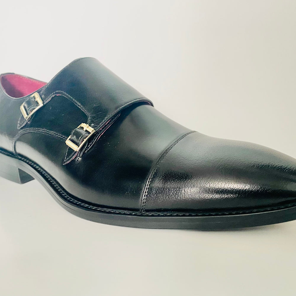 Black leather dress shoe with a buckle on a light gray background