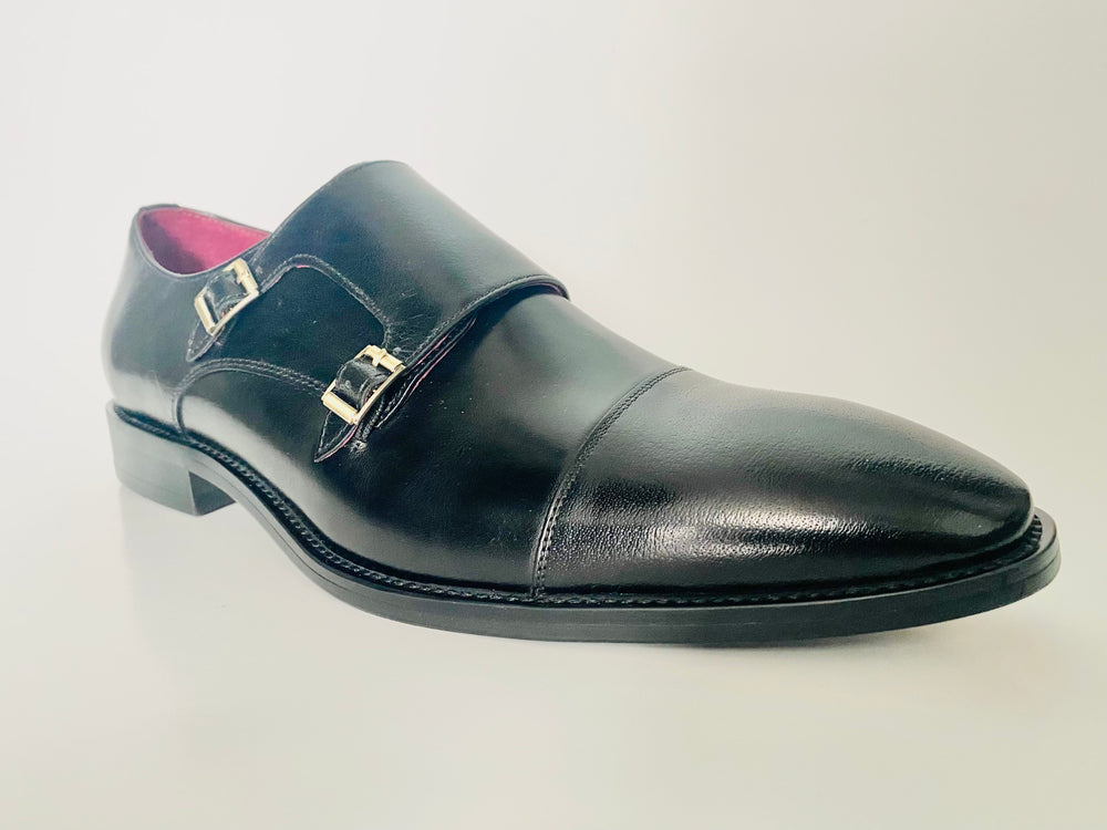 Black leather dress shoe with a buckle on a light gray background